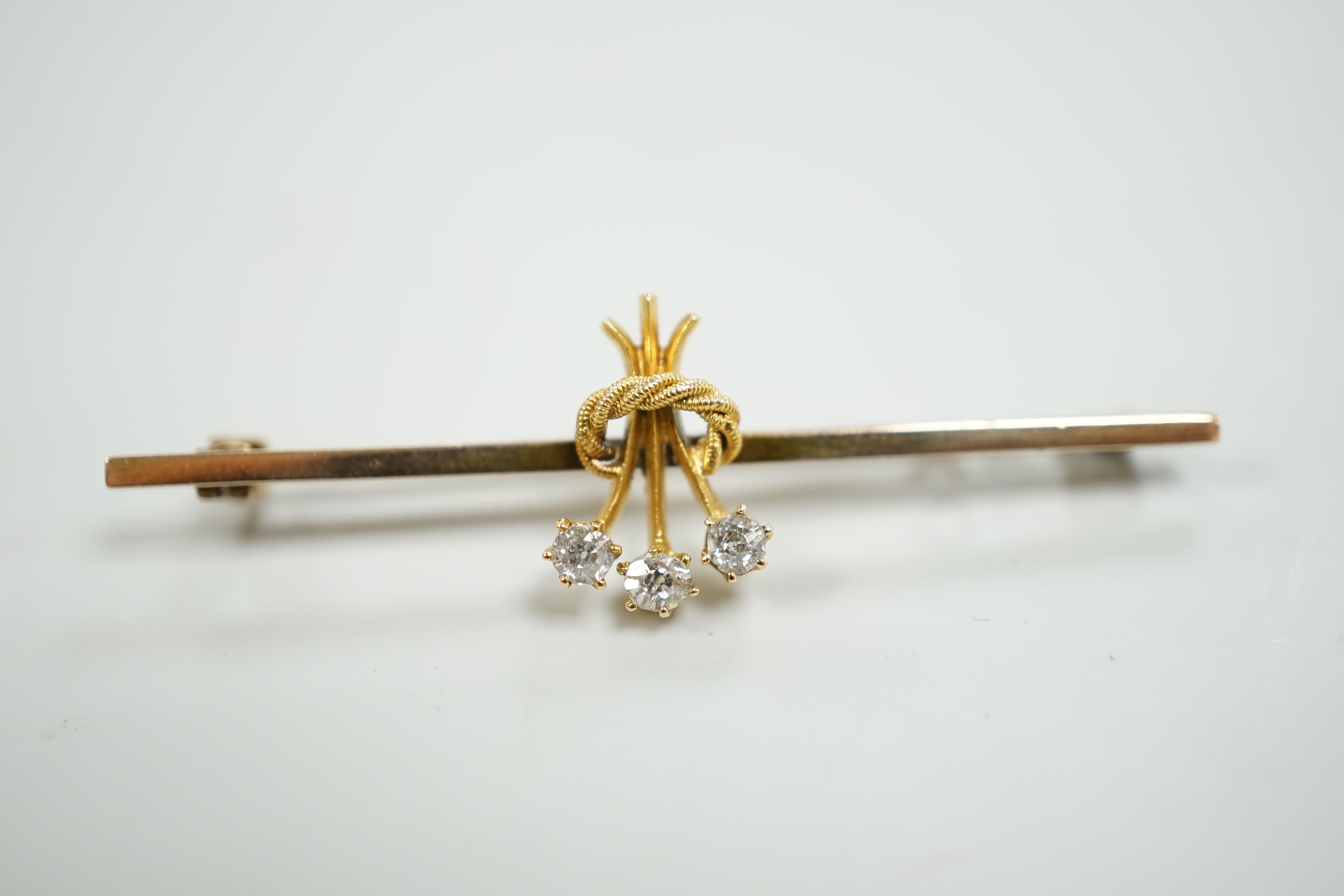 An Edwardian yellow metal and three stone diamond set bar brooch, 46mm, gross weight 2.5 grams.